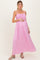 woman wearing a pink maternity maxi dress with smocked bodice and holding her baby bump