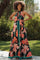 woman wearing a black floral maternity maxi dress with a halter neck and tie waist, showcasing her baby bump