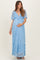 woman wearing a light blue lace maternity maxi dress with a tie front and short sleeves, cradling her baby bump