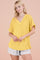 woman wearing a yellow short sleeve v-neck sweater with a relaxed fit and styled with light denim shorts