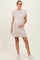 woman wearing a light beige maternity dress with short sleeves and a baby bump, styled with glasses and white sneakers