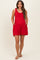 woman wearing a red maternity romper with tie straps and side pockets, showcasing her baby bump