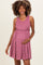 woman wearing a mauve ribbed maternity dress with a ruffled waist, gently holding her baby bump