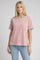 woman wearing a pink short sleeve t-shirt with turquoise trim and side slits, paired with light blue jeans