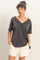 woman wearing a dark gray oversized v-neck t-shirt with short sleeves and relaxed fit, paired with cream shorts
