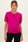 woman wearing a bright pink short sleeve maternity top with a relaxed fit and visible baby bump