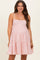 woman wearing a pink and white striped maternity dress with a tiered skirt and thin straps, showcasing her baby bump