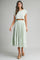 woman wearing a light green cropped top and matching pleated maxi skirt with a flowy silhouette and platform sandals