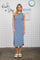 woman wearing a blue striped sleeveless midi dress standing against a tiled wall