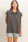 woman wearing a charcoal gray oversized polo shirt with a collar and button details, styled with light denim shorts