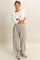 woman wearing a white long sleeve top and gray wide-leg sweatpants with pockets