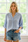 woman wearing a light blue button-up blouse with rolled sleeves and distressed denim shorts