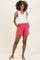 woman wearing a white sleeveless maternity top and pink maternity shorts with pockets