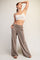 woman wearing a cream cropped tank top and taupe wide-leg pants with pockets, posed elegantly