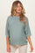 woman wearing a light green oversized maternity sweater with rolled sleeves and a visible baby bump