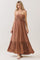 woman wearing a brown maxi dress with a ruffled bodice and spaghetti straps, standing against a neutral backdrop
