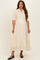 woman wearing a cream maternity dress with a smocked bodice, short sleeves, and button-down front, styled for comfort