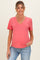 woman wearing a coral v-neck maternity top and showing her baby bump with light wash jeans