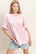 woman wearing a light pink oversized t-shirt with rolled sleeves and distressed denim shorts