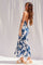 woman wearing a navy blue floral print maxi dress and white platform sandals, standing sideways against a light background
