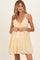 woman wearing a yellow maternity dress with adjustable straps and tiered design, showcasing a baby bump