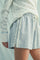 woman wearing a light gray flared shorts with floral detailing and a matching long sleeve sweater