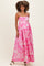 woman wearing a pink floral maternity maxi dress with adjustable straps and a flowy silhouette, showing her baby bump