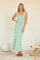 woman wearing a green and white striped sleeveless maxi dress, standing casually with one hand on her hip