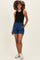 woman wearing a black sleeveless top and blue maternity shorts with an elastic waistband and pockets