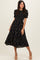 woman wearing a black floral puff sleeve midi dress with a smocked bodice and a flowing skirt