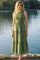woman wearing a green polka dot tiered midi dress posed by a lake