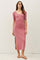 woman wearing a pink ribbed midi dress with short sleeves and side slit, standing against a plain background