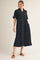 woman wearing a black button-up shirt dress with short sleeves and pockets, styled with brown sandals