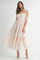 woman wearing a floral print pastel maxi dress with a sweetheart neckline and bow tie straps