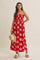 woman wearing a red floral maxi dress with a square neckline and spaghetti straps, holding a straw hat