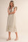 woman wearing a cream striped midi dress with ruffled sleeves and a tiered hem, paired with wedge sandals