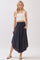 woman wearing a white cropped tank top and a dark navy maxi skirt with pockets, standing in a casual pose