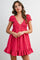 woman wearing a pink short puff sleeve dress with a smocked bodice and ruffle hem, featuring front buttons