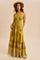 woman wearing a mustard green halter neck maxi dress with a bohemian print and pockets, accessorized with a wide-brim hat
