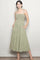 woman wearing a green and white gingham midi dress with adjustable tie straps and side pockets