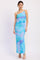 woman wearing a colorful one-shoulder maxi dress with a flowing silhouette and abstract floral print