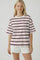 woman wearing a white short sleeve striped t-shirt with red, navy, and blue stripes and white shorts