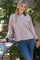 woman wearing a pink and brown striped long sleeve polo shirt with a relaxed fit and blue jeans