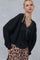 woman wearing a black cable knit cardigan over a black lace cami and a leopard print skirt, with layered necklaces