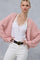 woman wearing a light pink oversized cable knit cardigan over a white lace camisole and white high-waisted pants