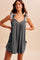 woman wearing a charcoal gray romper with checked tie straps and front pockets