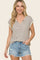 woman wearing a beige and brown striped short sleeve top with a v-neck and paired with denim cut-off shorts