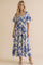 woman wearing a floral print maxi dress with blue and cream colors, short sleeves, and a smocked bodice