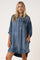 woman wearing a oversized denim shirt dress with long sleeves and a front pocket