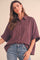 woman wearing a burgundy and white checkered oversized button-up shirt with short sleeves and light blue jeans